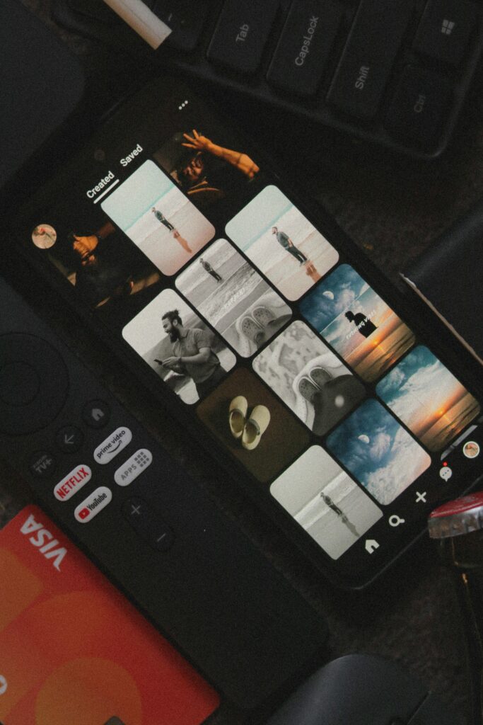 A smartphone displays an image gallery surrounded by a remote control and a credit card.
